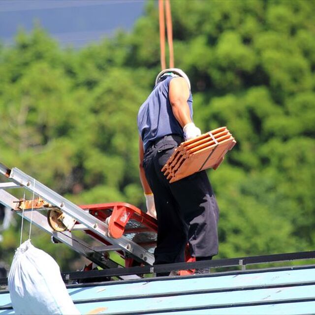 リフトで瓦を屋根に揚げる職人